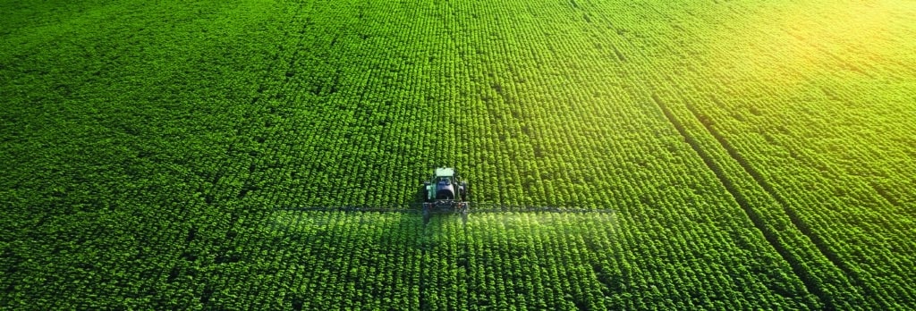 Drone point of view of a tractor spraying foliar fertilizer on a soybean field. This is a good way to prevent or correct calcium deficiency.