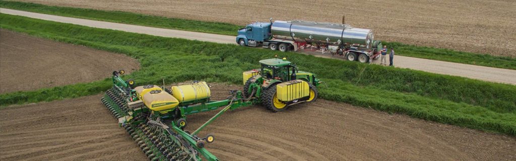 A tractor parked next to an AgroLiquid delivery truck